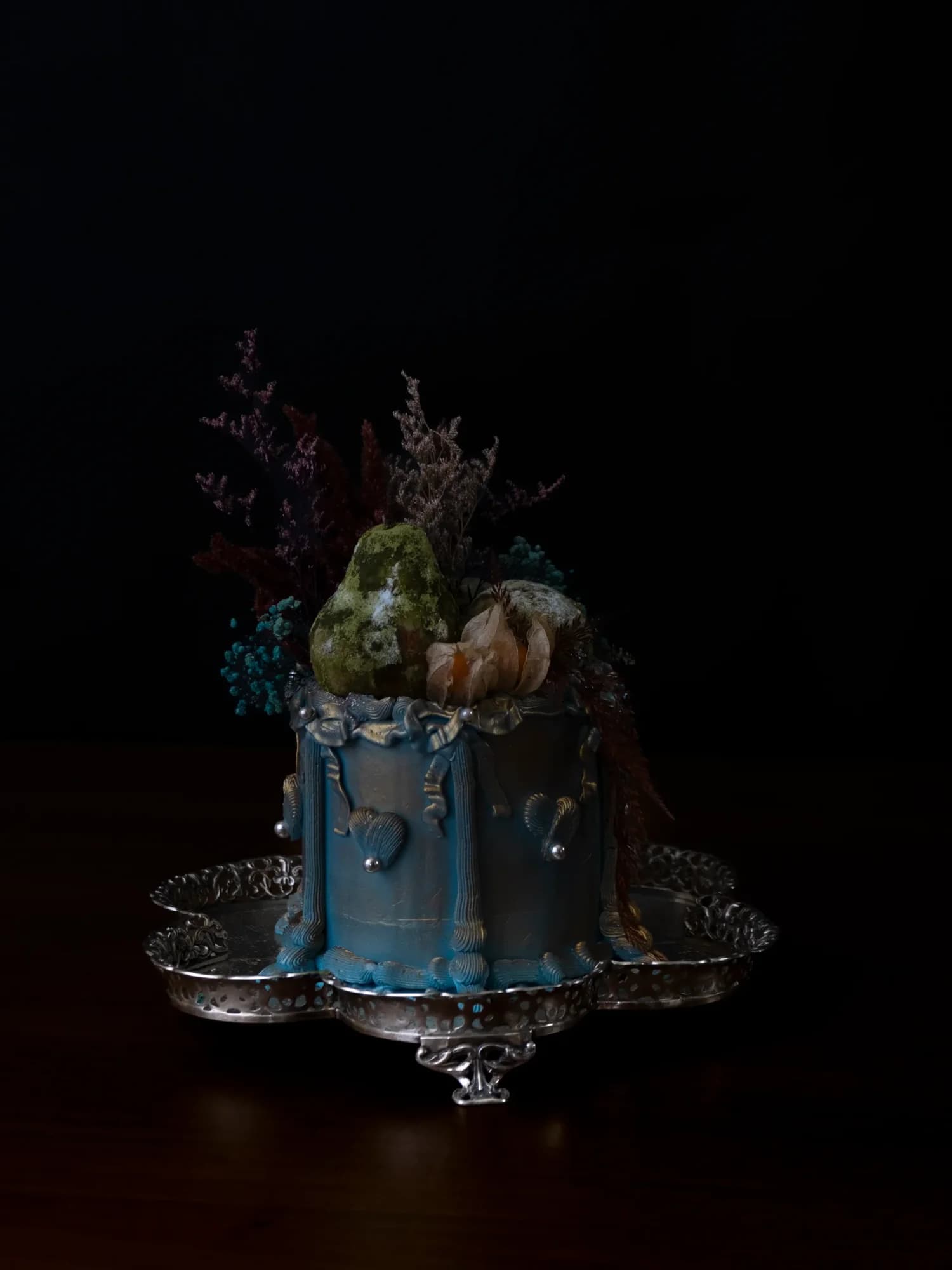 Blue drip cake topped with moss pear and dried flowers