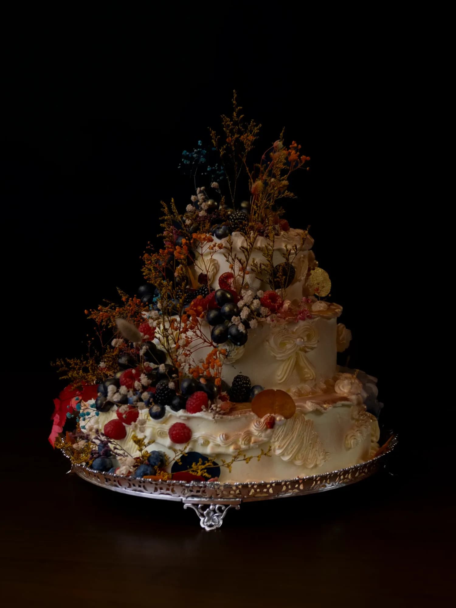 Elaborate three-tier cake with berries and dried flowers
