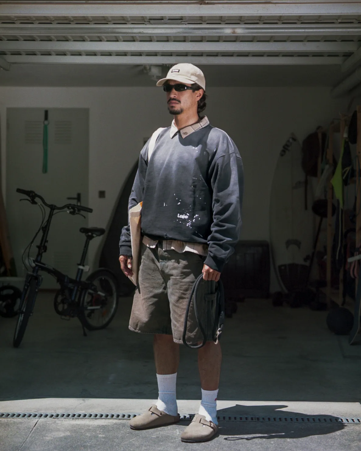 Man in grey Laje sweatshirt, garage doorway, bicycle behind