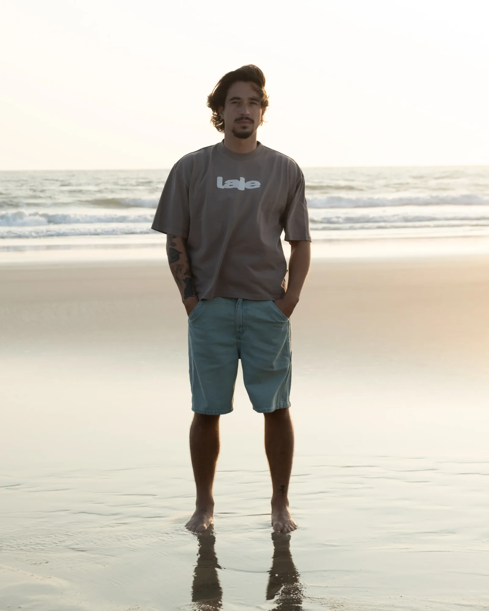 Model on shoreline at sunset, ocean behind